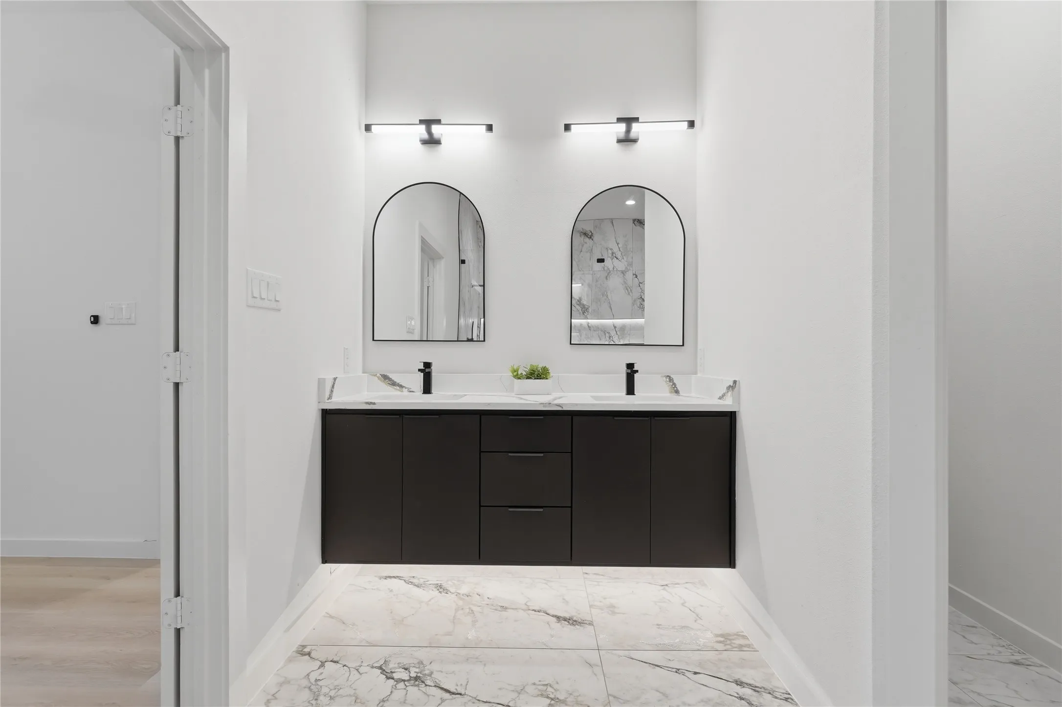 Dual vanity with black cabinetry, white countertop, and arched mirrors