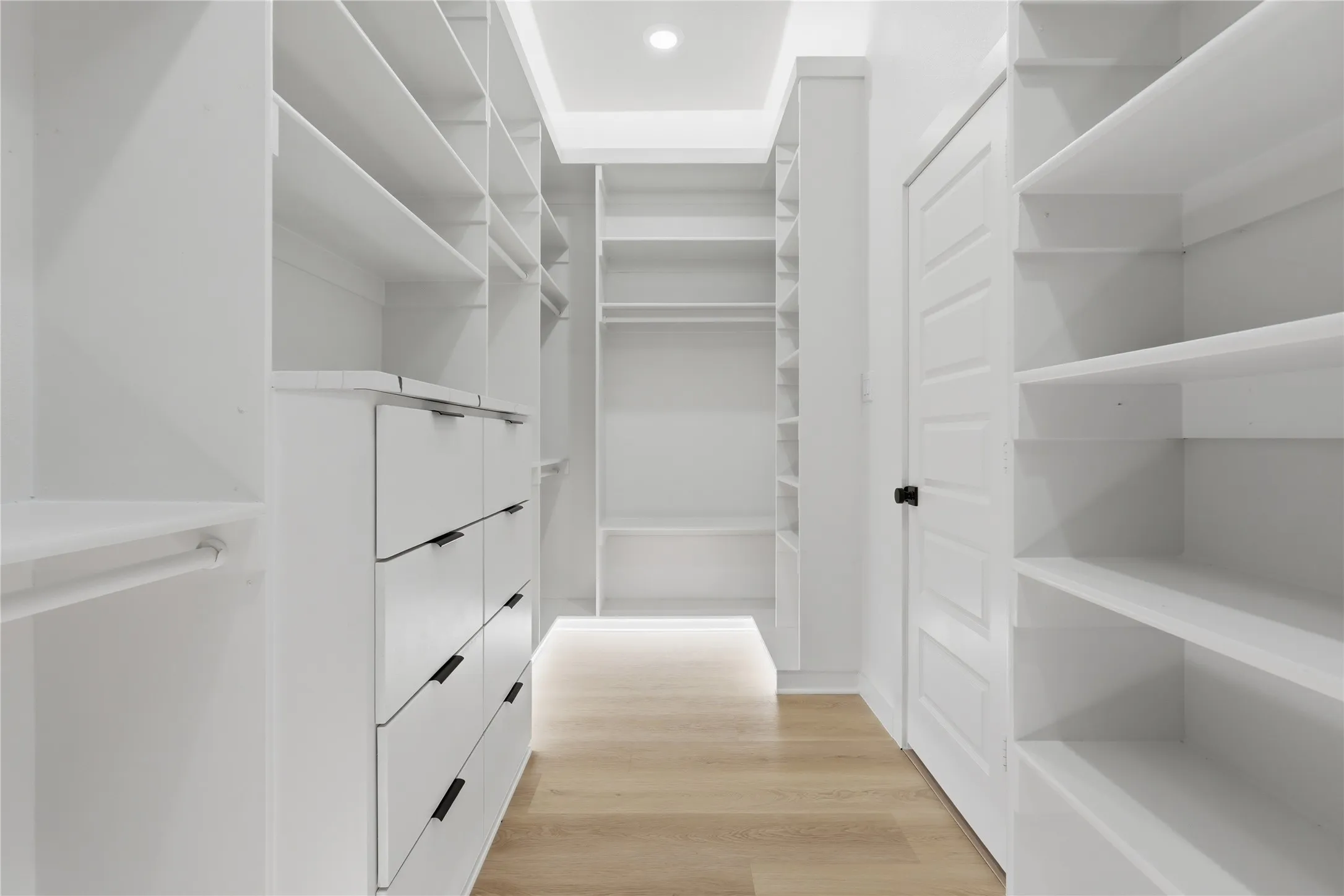 Built-in shelving units, integrated drawer storage, recessed lighting, and wood-finish flooring