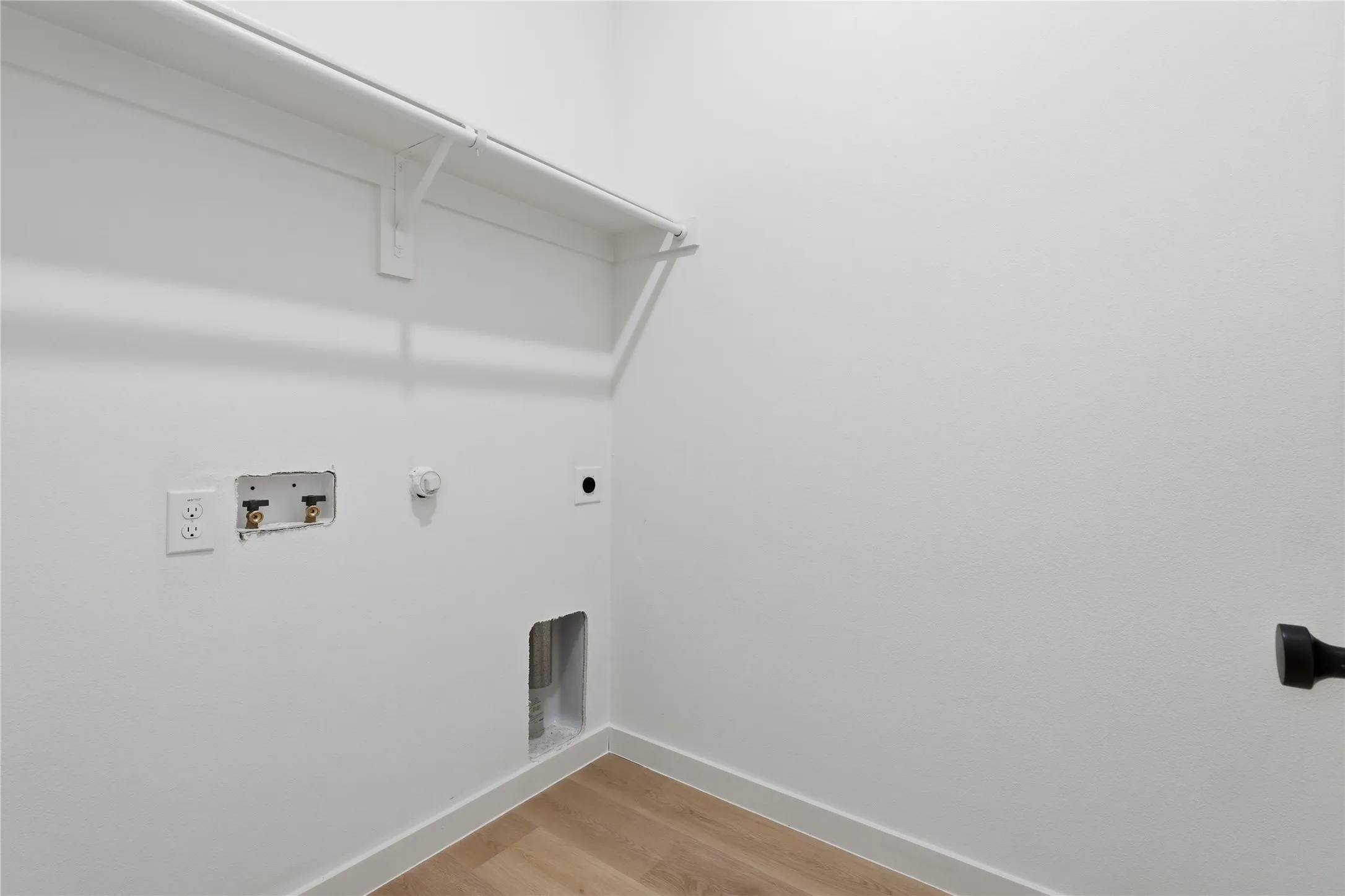 Laundry area with wood-finish flooring, white walls, and built-in shelving