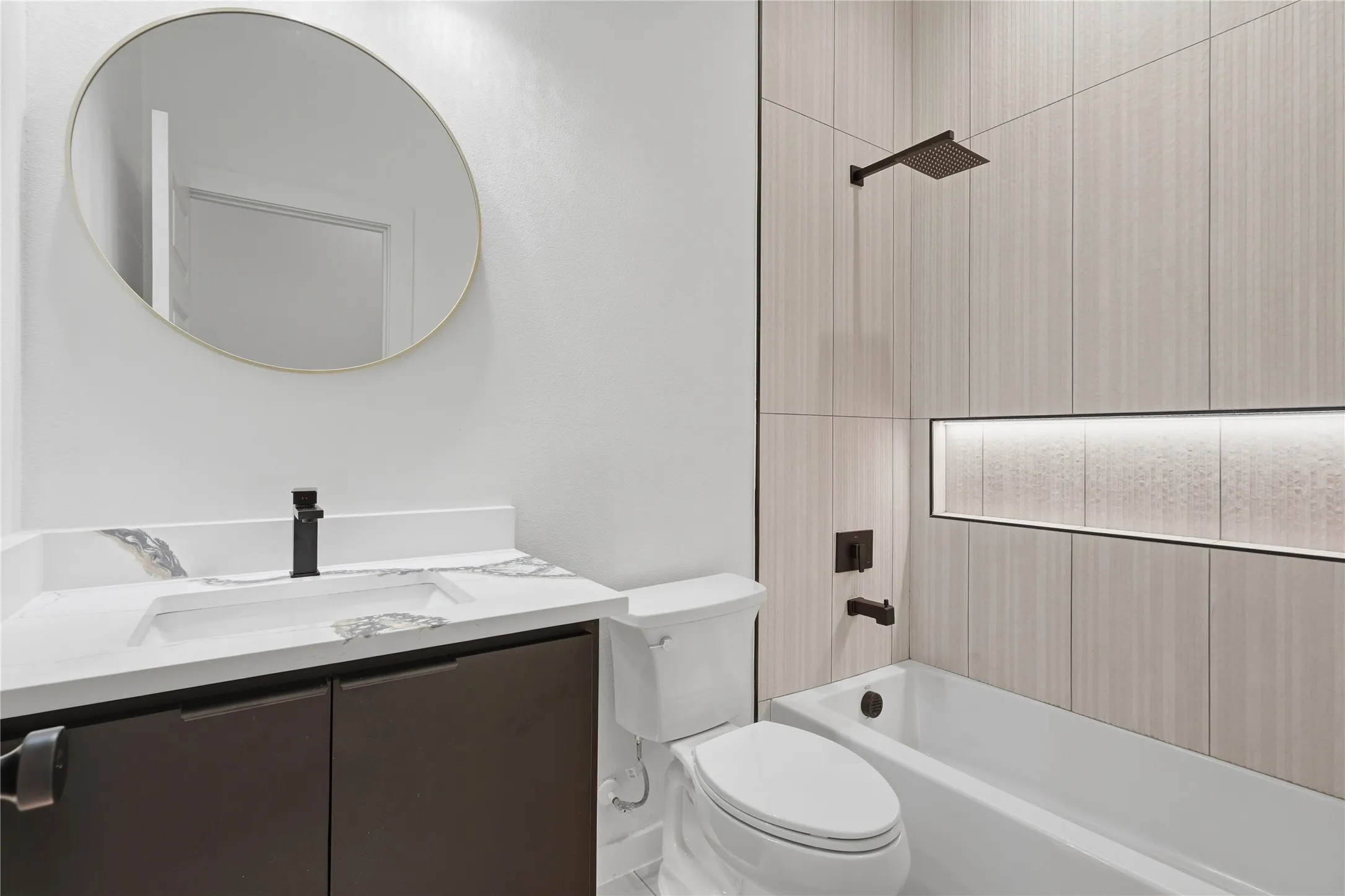 Modern bathroom featuring a vanity with dark cabinetry, integrated sink, and matte black fixtures