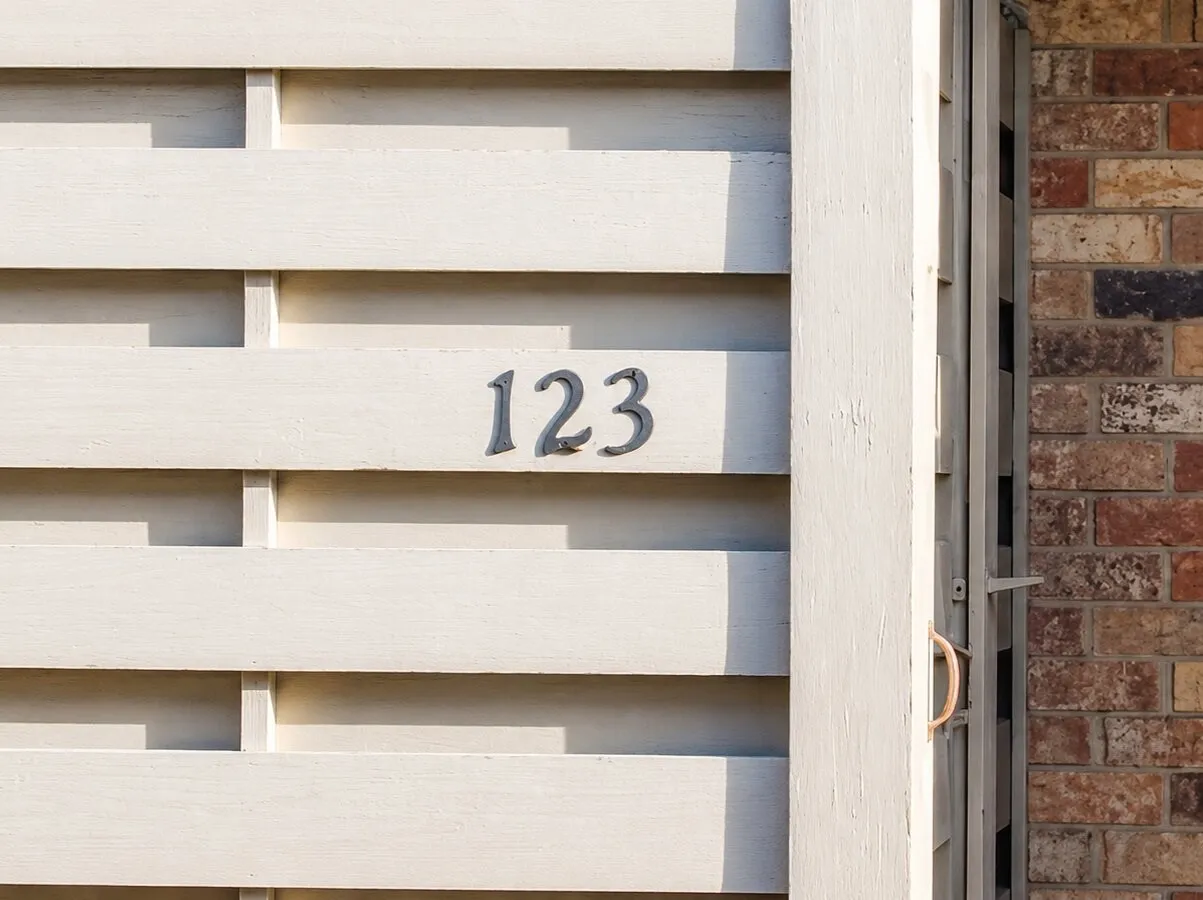Decorative house numbers on a light-toned horizontal slatted panel, complemented by a brick exterior