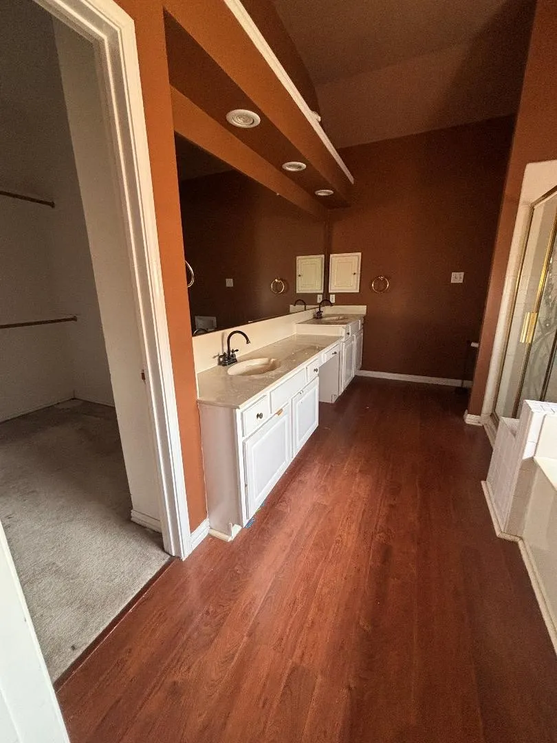 Master bath with dual sinks and counter space, leading to walk in closet.
