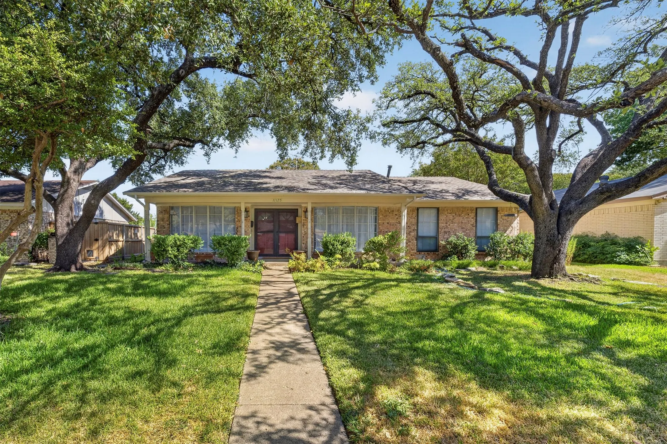 Brick facade with a covered front porch and established landscaping