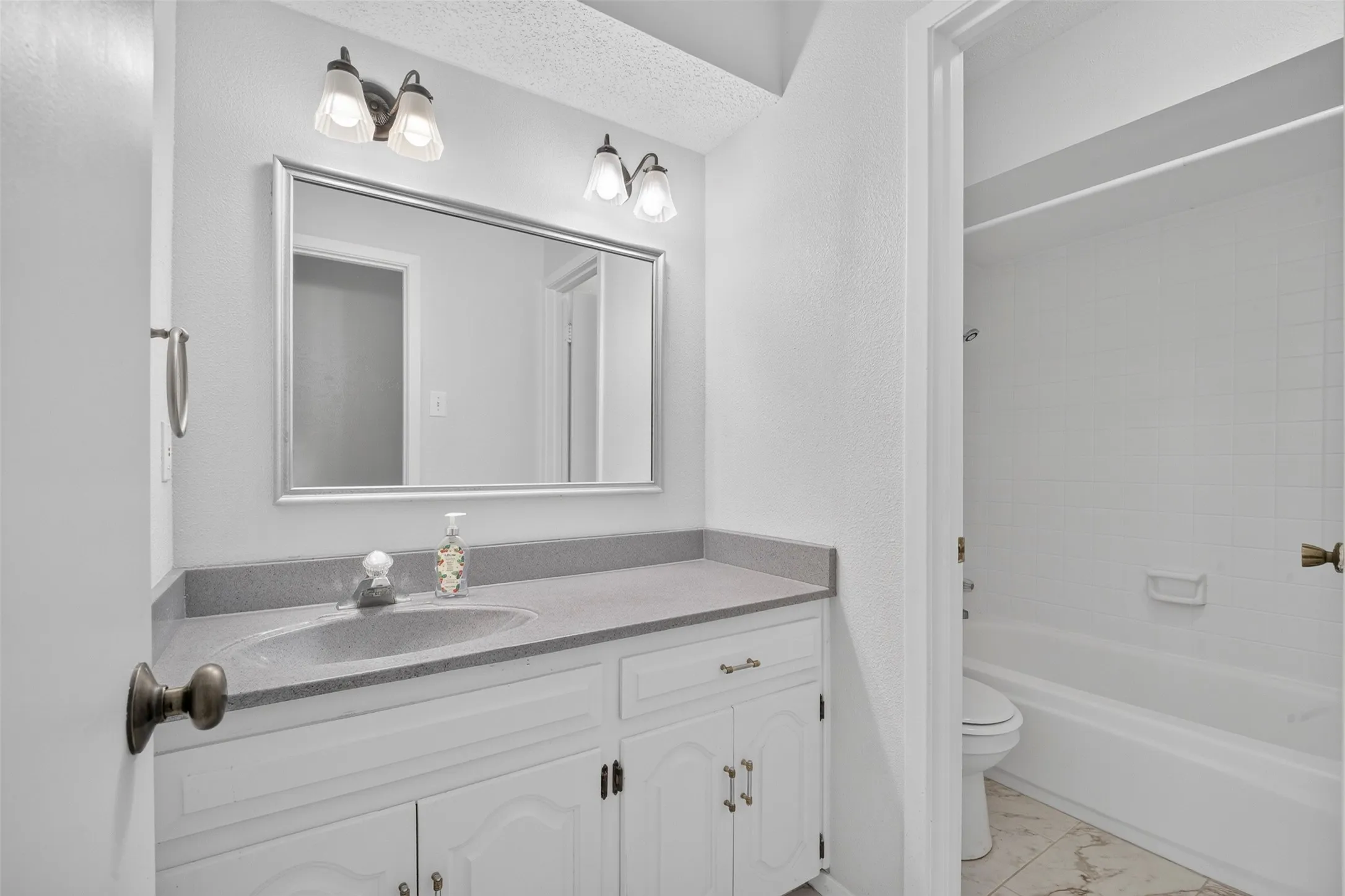 Vanity with an integrated sink, broad mirror, and overhead sconce lighting