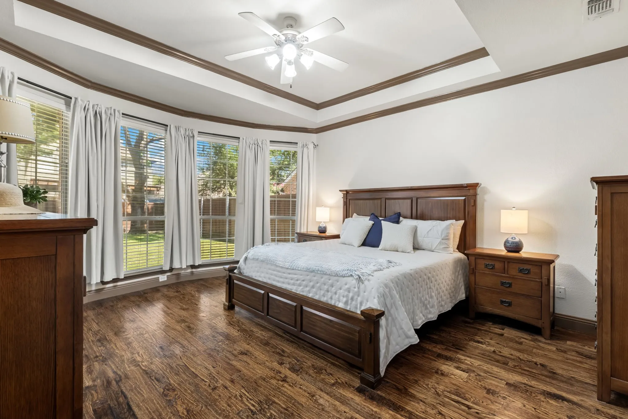 Primary suite with quality hardwood flooring and sweeping views of the backyard.
