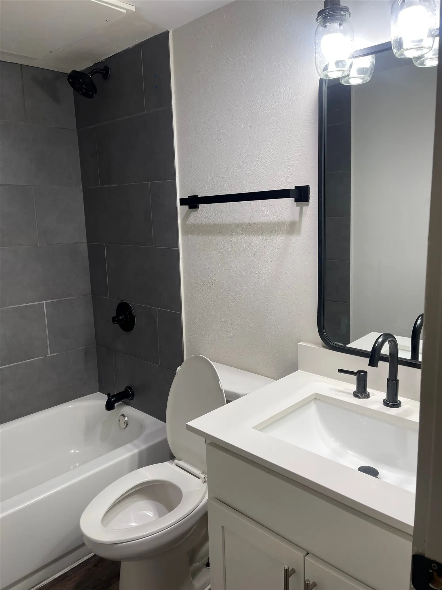 Bathroom featuring white vanity with integrated sink, matte black faucet, and framed mirror with integrated lighting