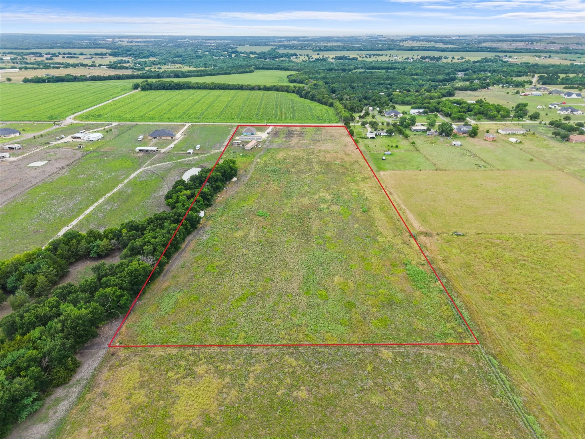 Expansive land parcel outlined in red, featuring open fields and distant agricultural areas