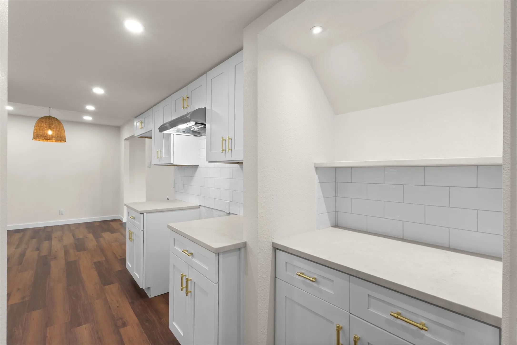 White shaker cabinetry with gold-finish hardware, light-toned countertops, and subway tile backsplash