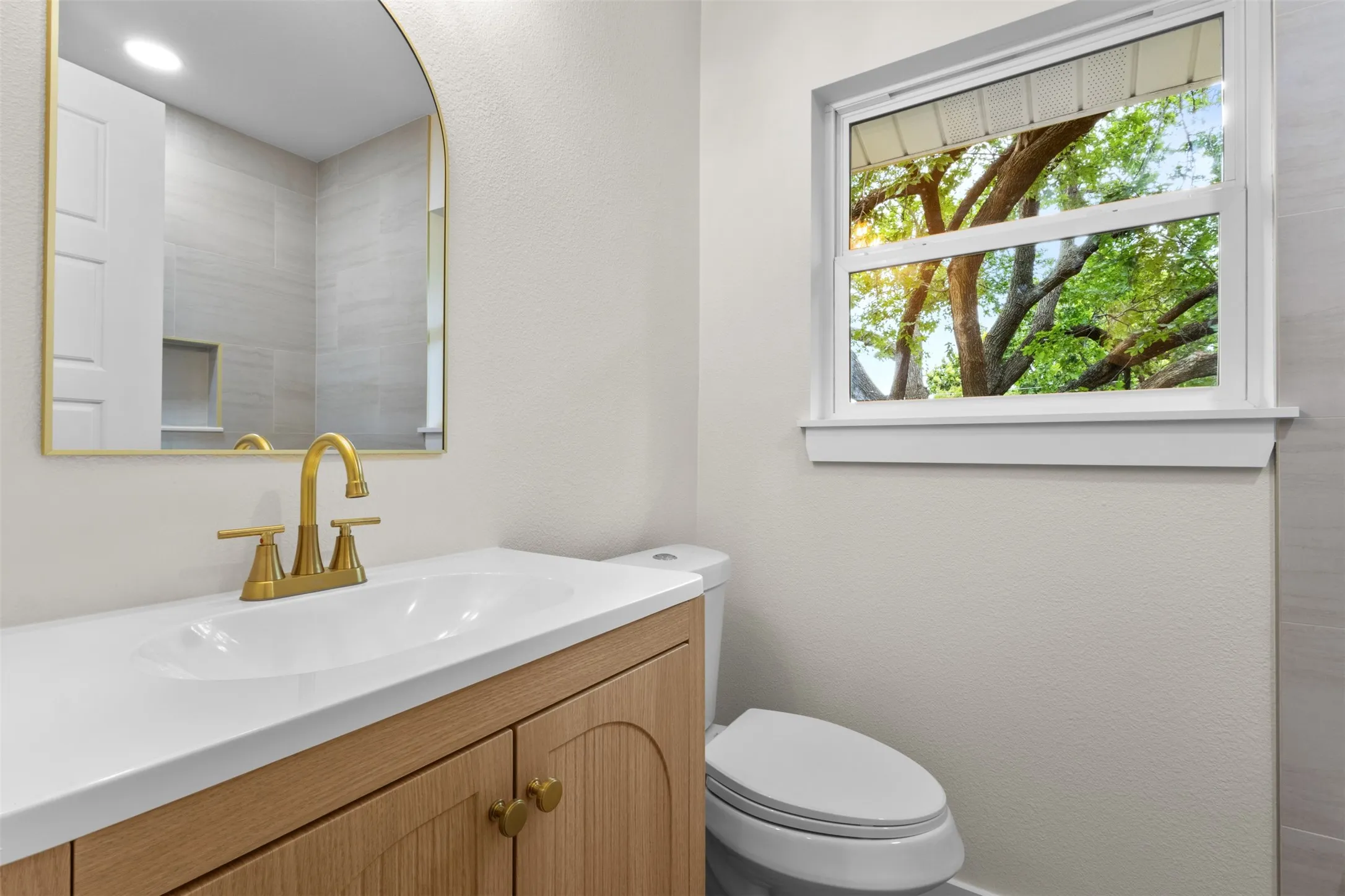 Vanity with a white countertop and integrated sink, gold-finish faucet, and wood-finish cabinetry