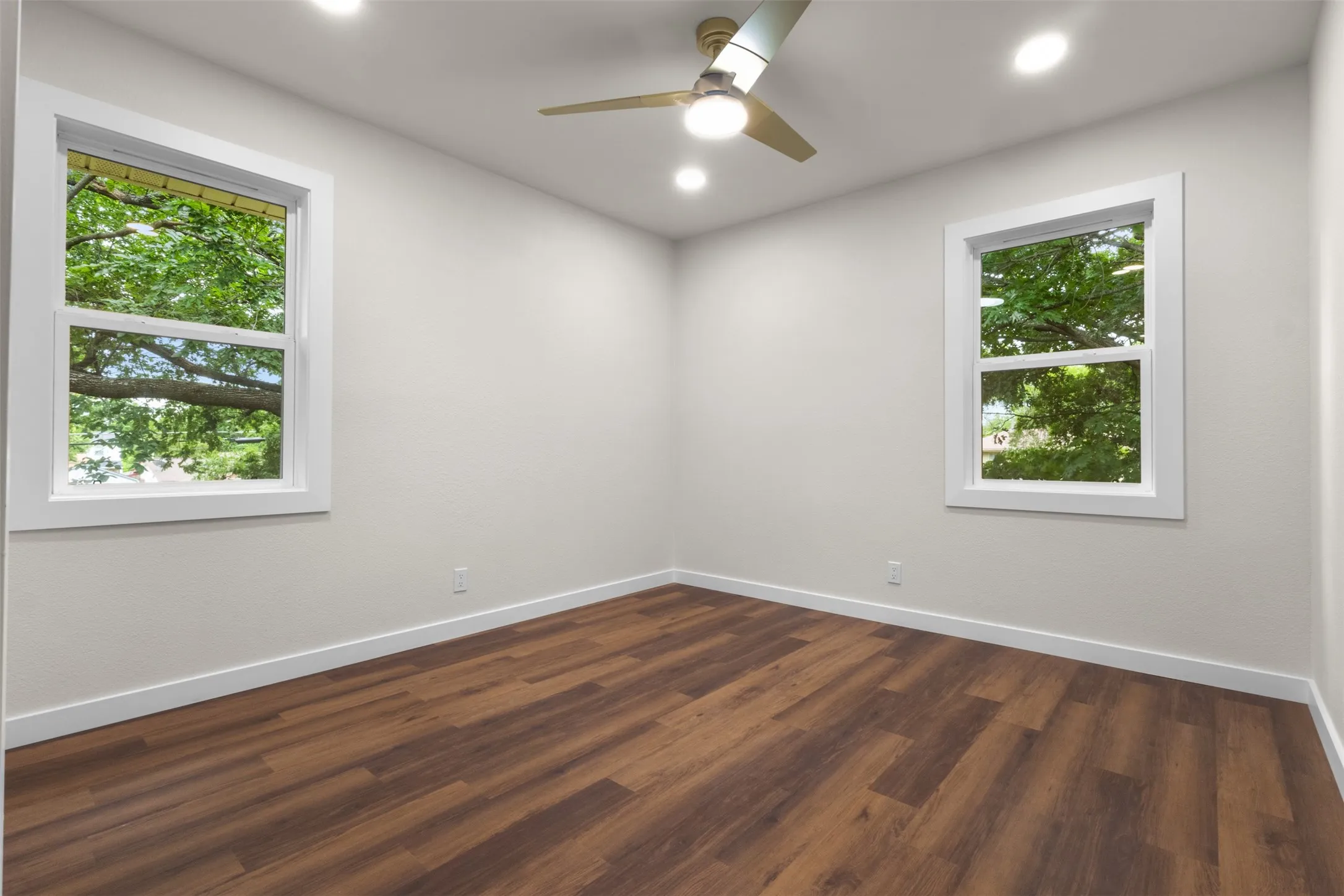 Wood-finish flooring, recessed lighting, ceiling fan, and white trim