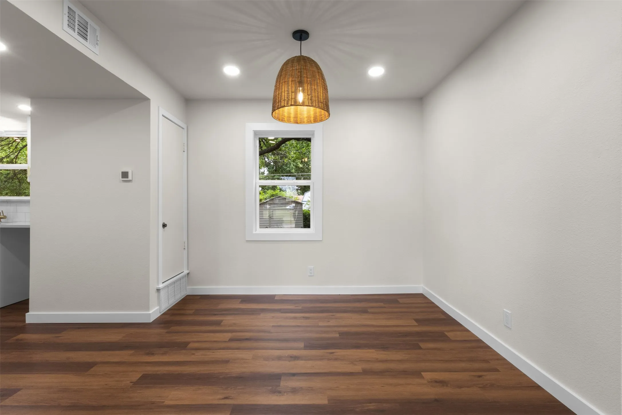 Wood-finish flooring throughout, recessed lighting, and a woven pendant light fixture