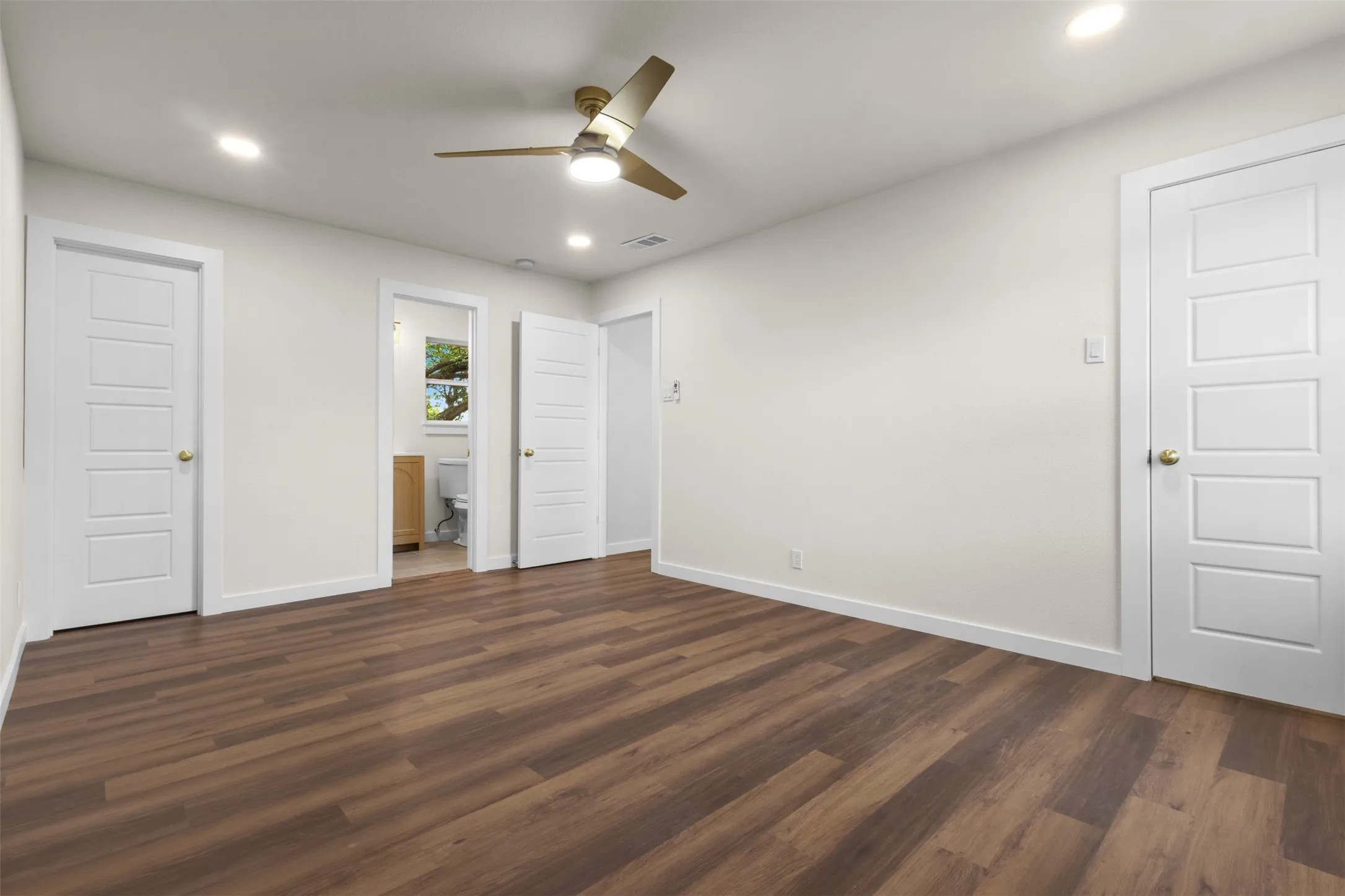 Wood-finish flooring, recessed lighting, ceiling fan with light, white paneled doors, and a neutral wall color