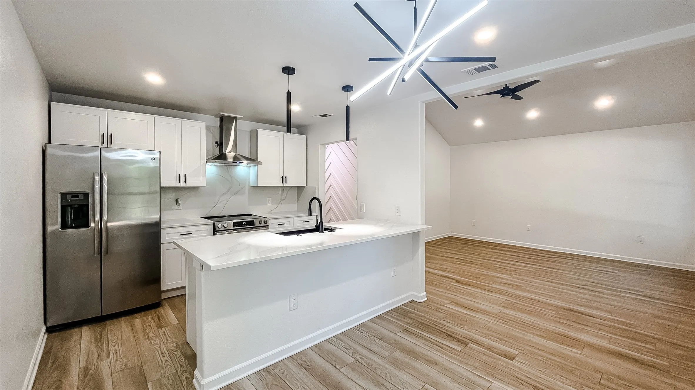 Updated kitchen boasting a spacious island bar, sleek counters, and stainless steel appliances.