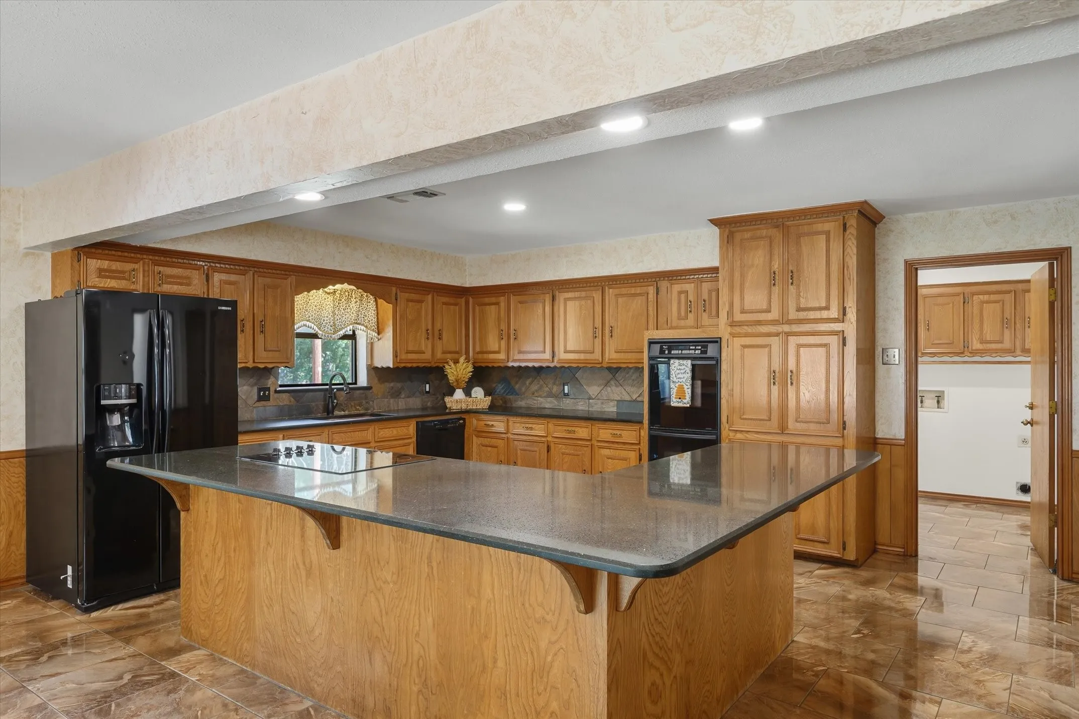 Expansive kitchen with large eating and serving island, double ovens, and beautiful cabinetry.