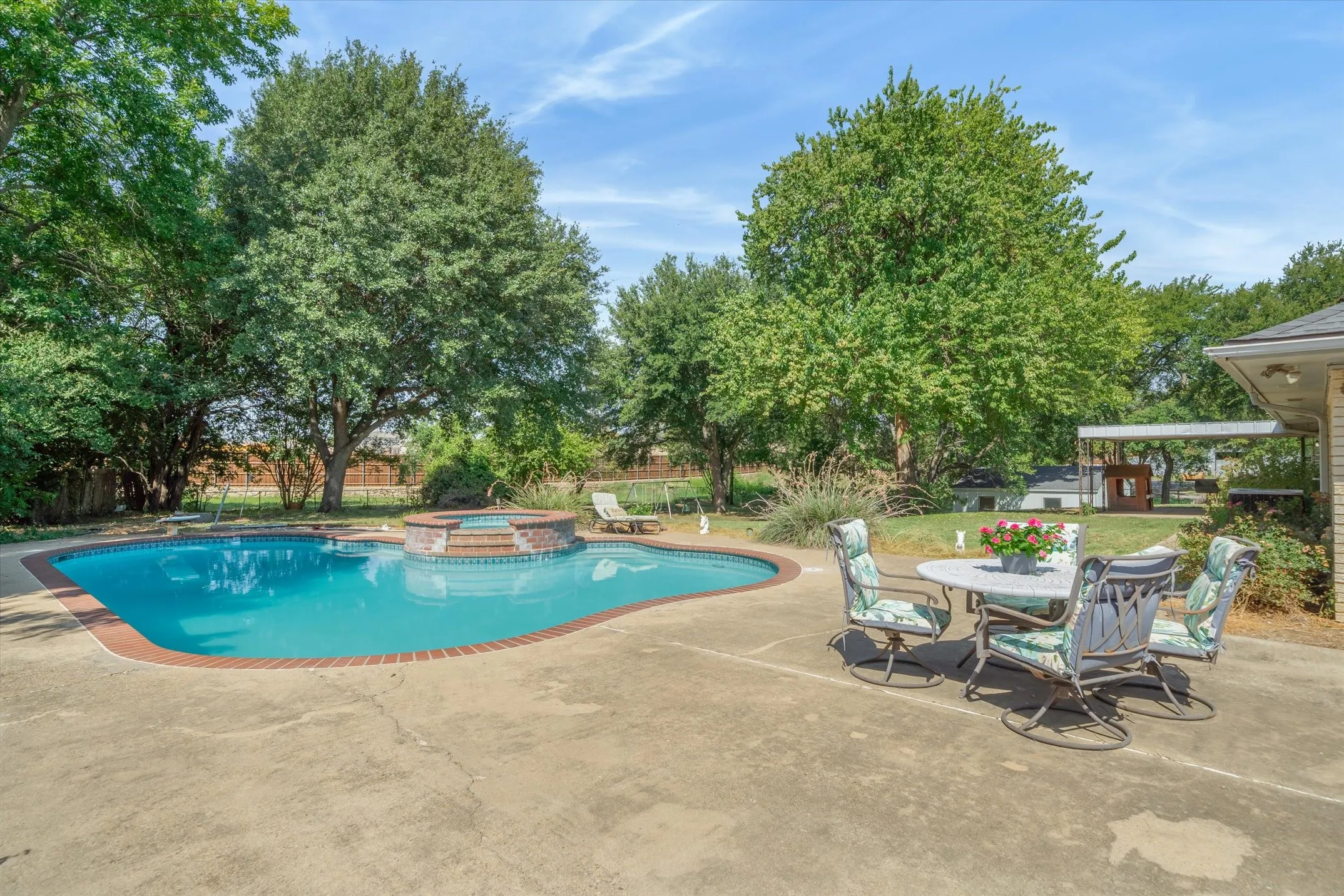 A large patio area surrounds the sparkling in-ground pool and raised spill-over spa, also highlighted by perennial, easy-care landscaping