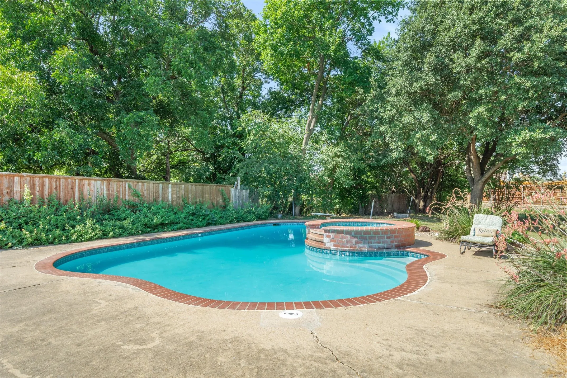 A sparkling in-ground pool and raised spill-over spa highlighted by perennial, easy-care landscaping