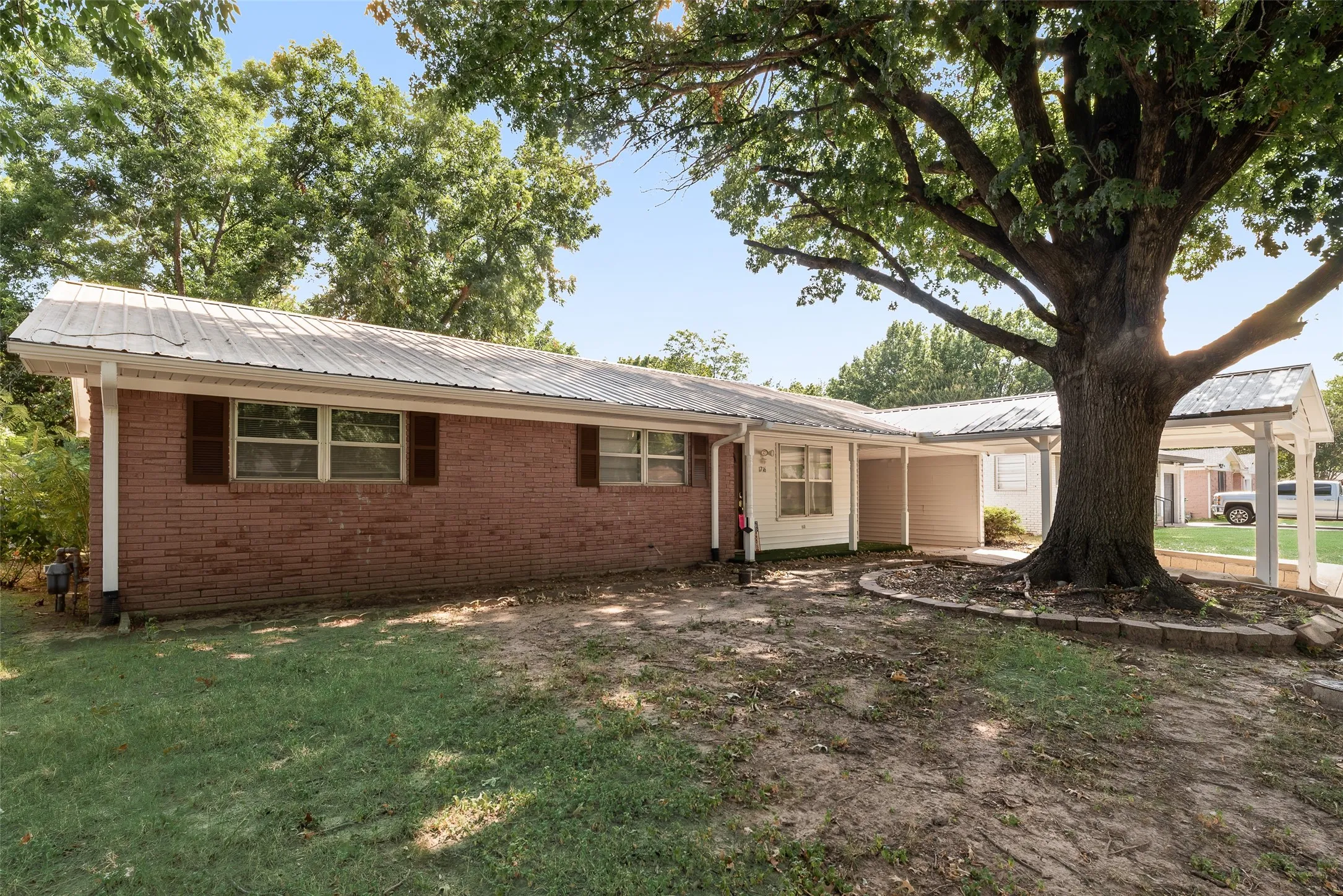 Brick exterior with a metal roof and an attached carport