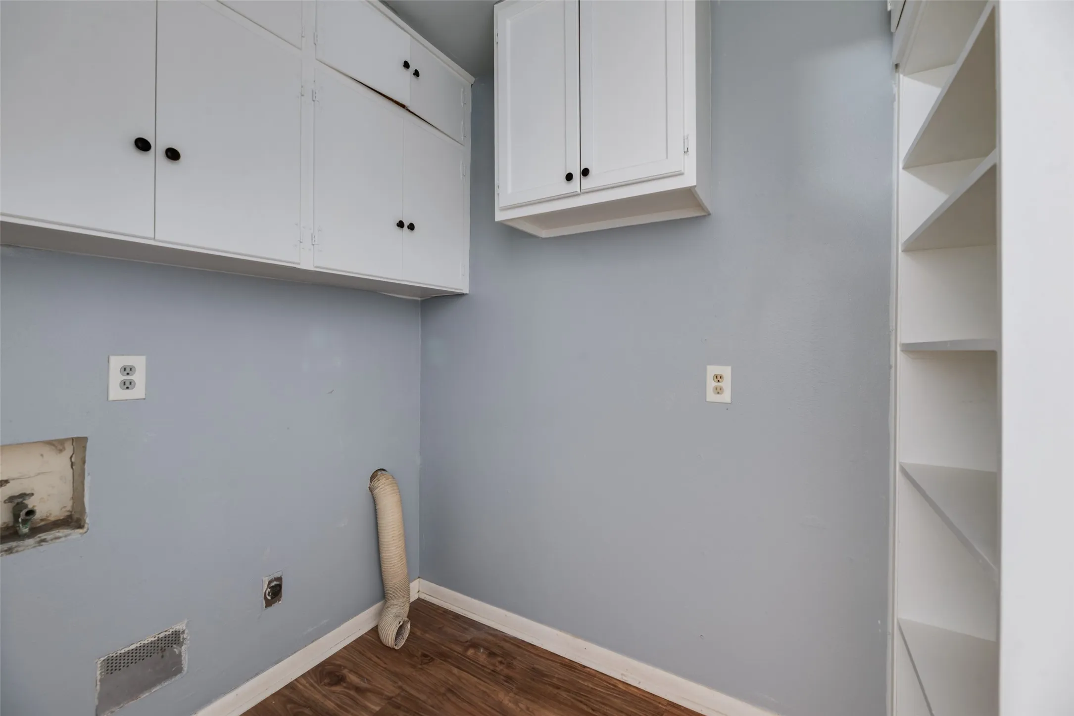 White upper cabinetry, built-in shelving, and wood-finish flooring