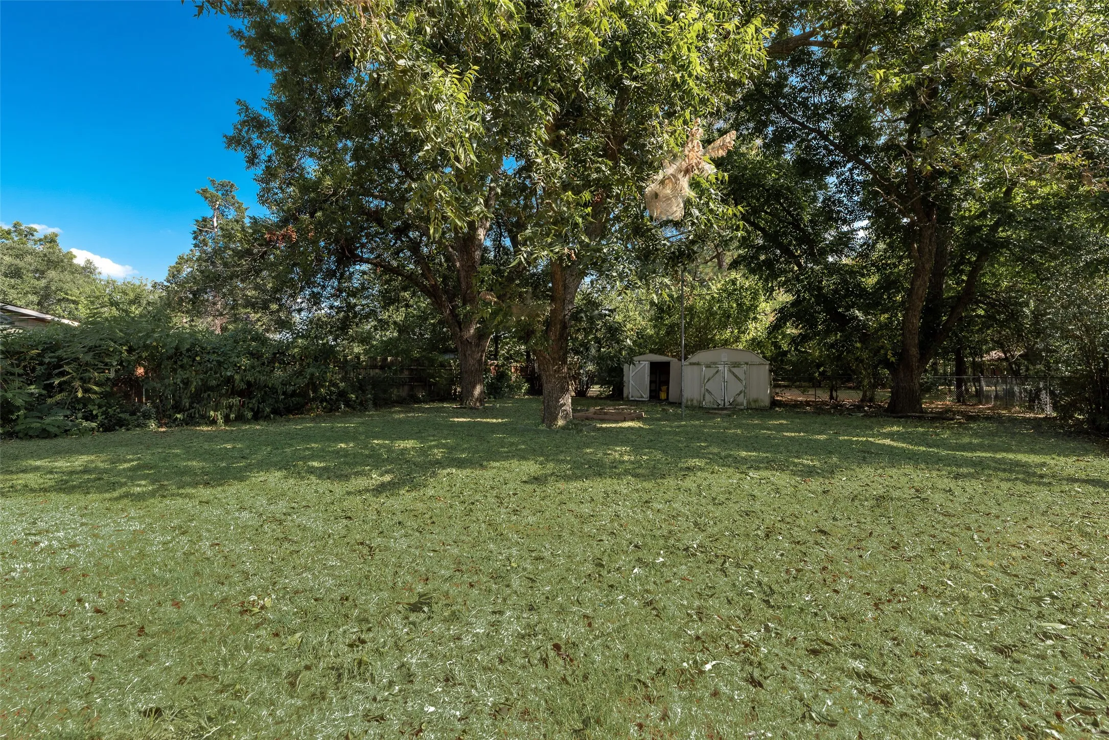 Expansive grassy yard with mature trees providing ample shade