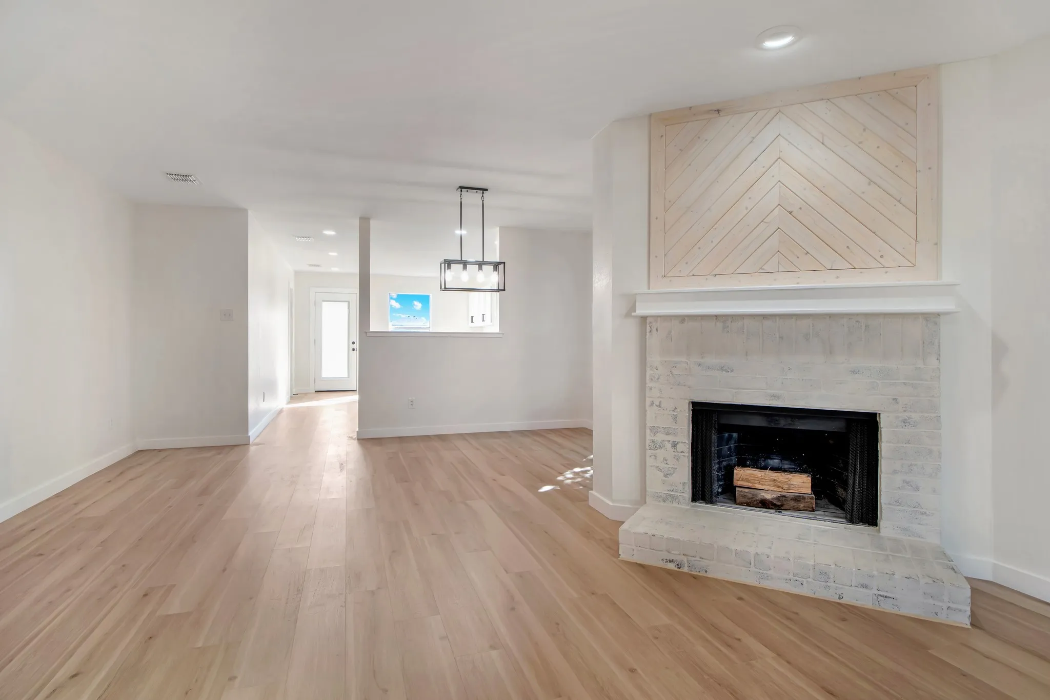 Wood-finish flooring with white baseboards, a window with horizontal blinds, and a closet with bifold doors and black hardware