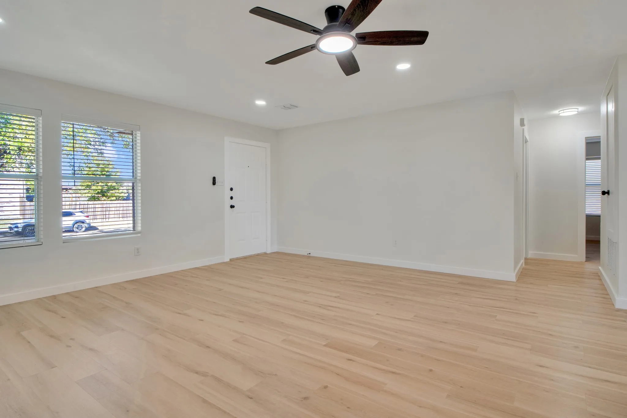 Wood-finish flooring, white walls, and a white interior door with black hardware