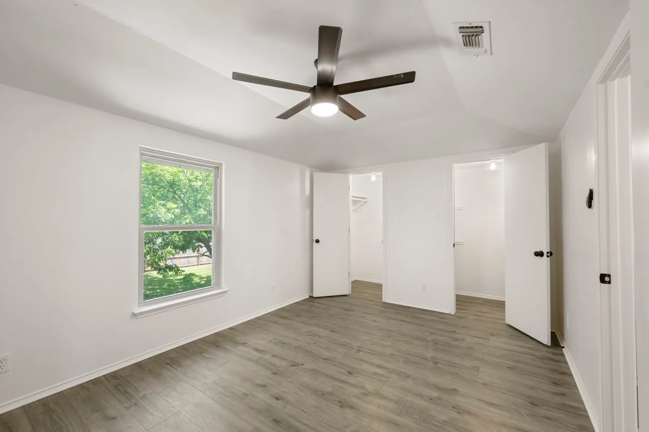 Room featuring wood-finish flooring, a ceiling fan, and two built-in closet spaces