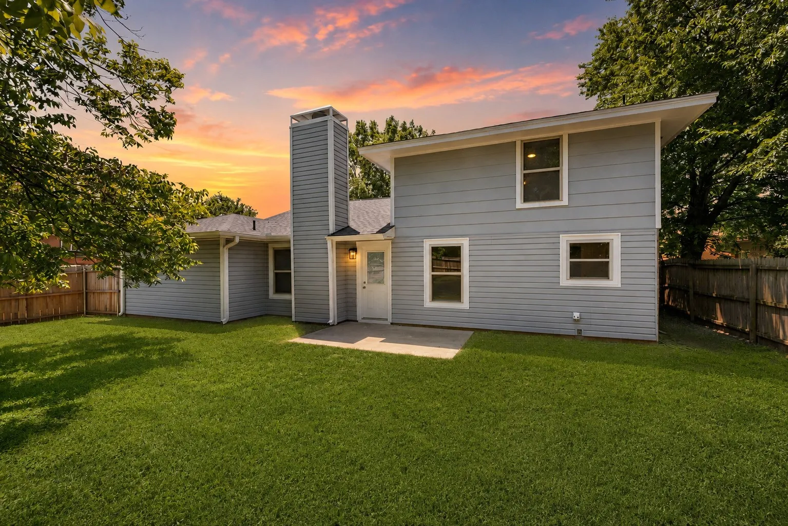 Spacious backyard with a grass lawn, wood fencing, and a concrete patio