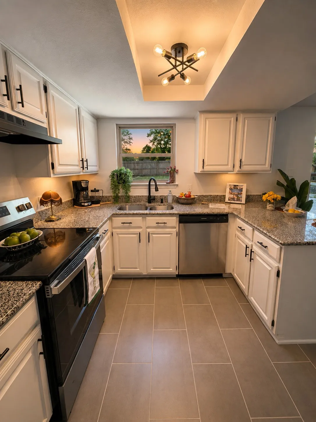 U-shaped kitchen with white cabinetry and dark pulls, granite-finish countertops, stainless steel appliances, and rectangular floor tiles