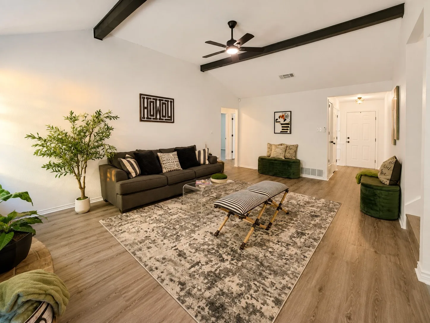 Vaulted ceilings with exposed beams, wood-finish flooring, a ceiling fan, and a white paneled entry door
