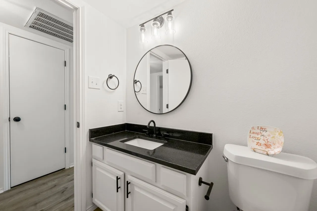 White vanity with black countertop, under-mount sink, and matte black faucet