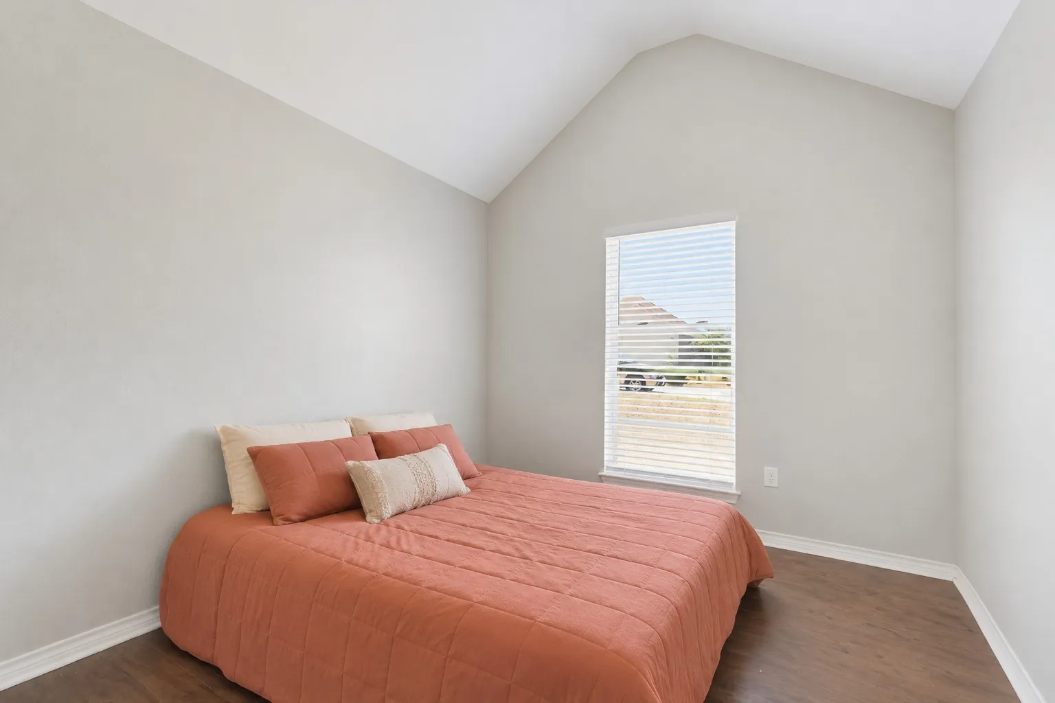 Vaulted ceiling, wood-finish flooring, white trim, single window with blinds