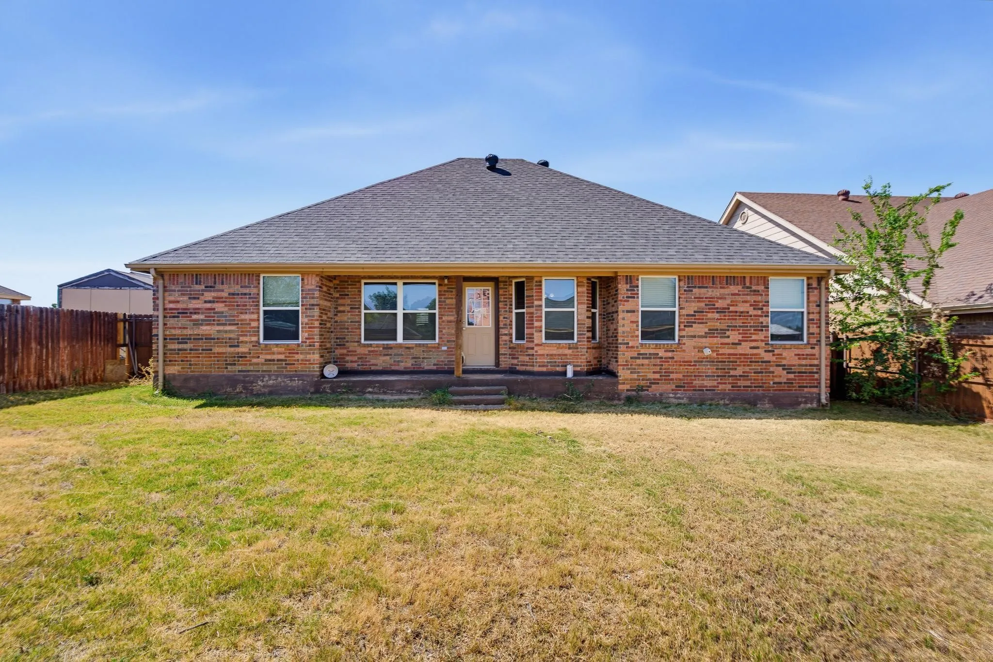 Brick exterior with multiple windows and a shingle roof