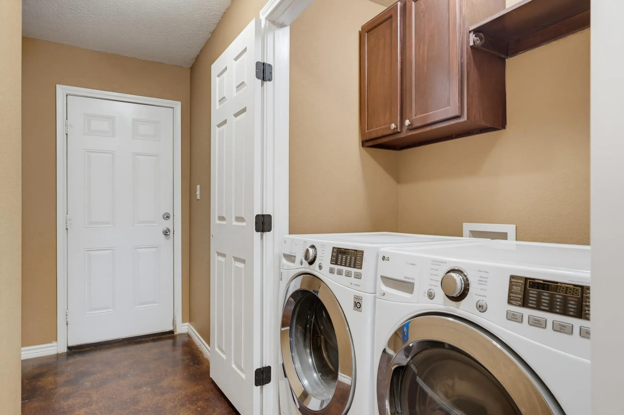 Laundry area featuring wood-finish flooring, built-in upper cabinetry, and a storage shelf
