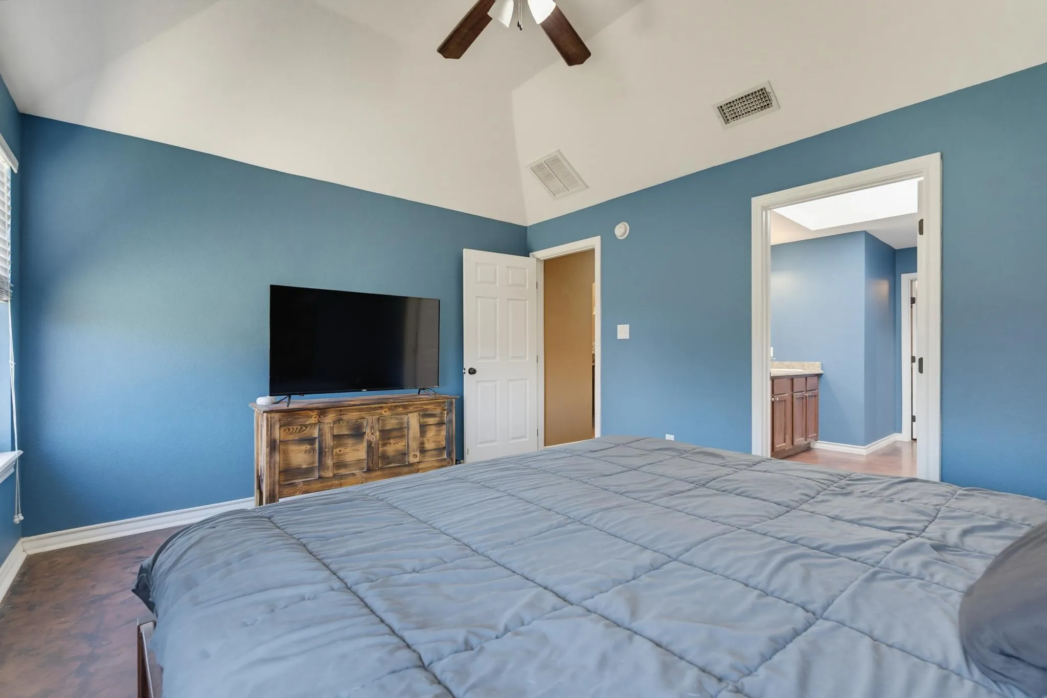 Vaulted ceiling, ceiling fan, wood-finish flooring, white door, light-colored walls
