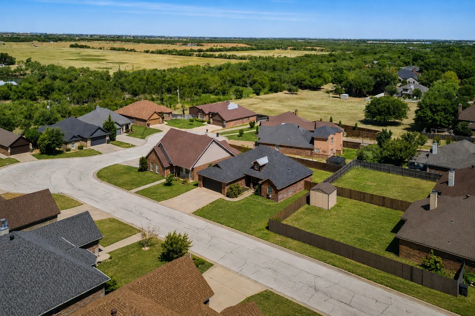 Residential cul-de-sac with brick and siding exteriors, asphalt shingle roofs, and green landscaping