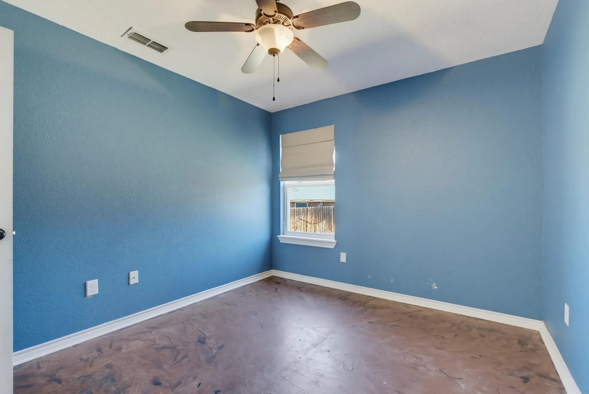 Ceiling fan with integrated lighting, single window with roller shade, and textured blue walls