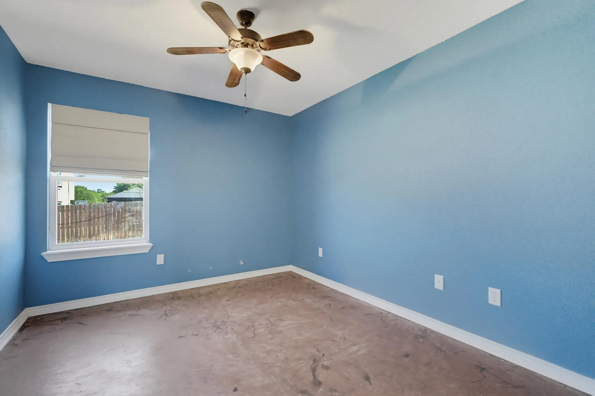 Textured blue walls, white trim, wood-finish ceiling fan with integrated lighting, and window with white frame
