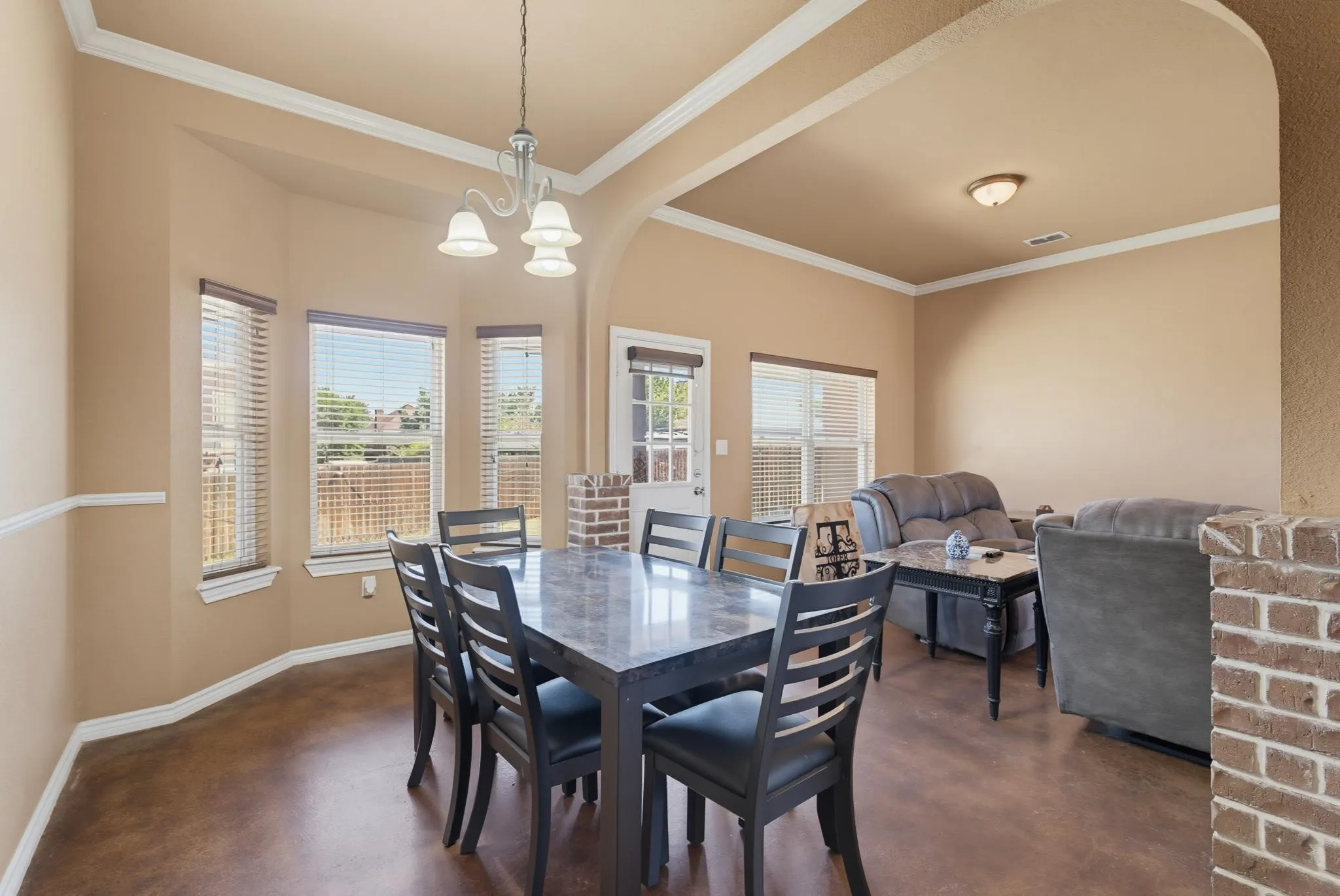 Bay window with multiple panels, crown molding, chair rail molding, and a chandelier