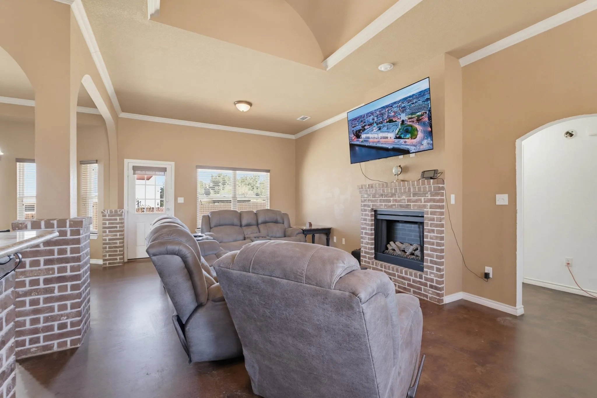 Brick fireplace with a hearth, arched entryways, tray ceiling, and a glass-paneled exterior door
