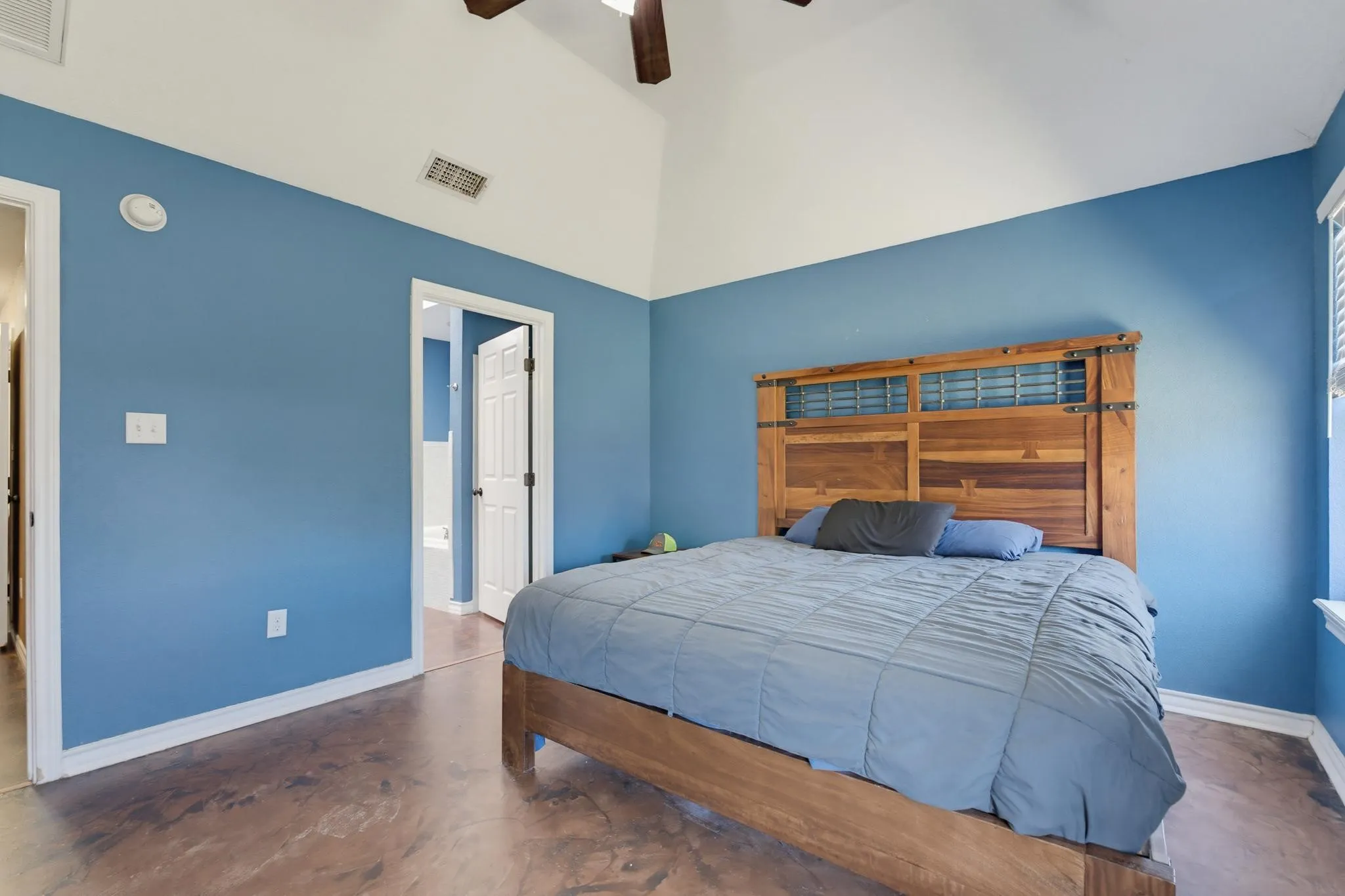Vaulted ceiling with a ceiling fan, stained concrete flooring, and white trim