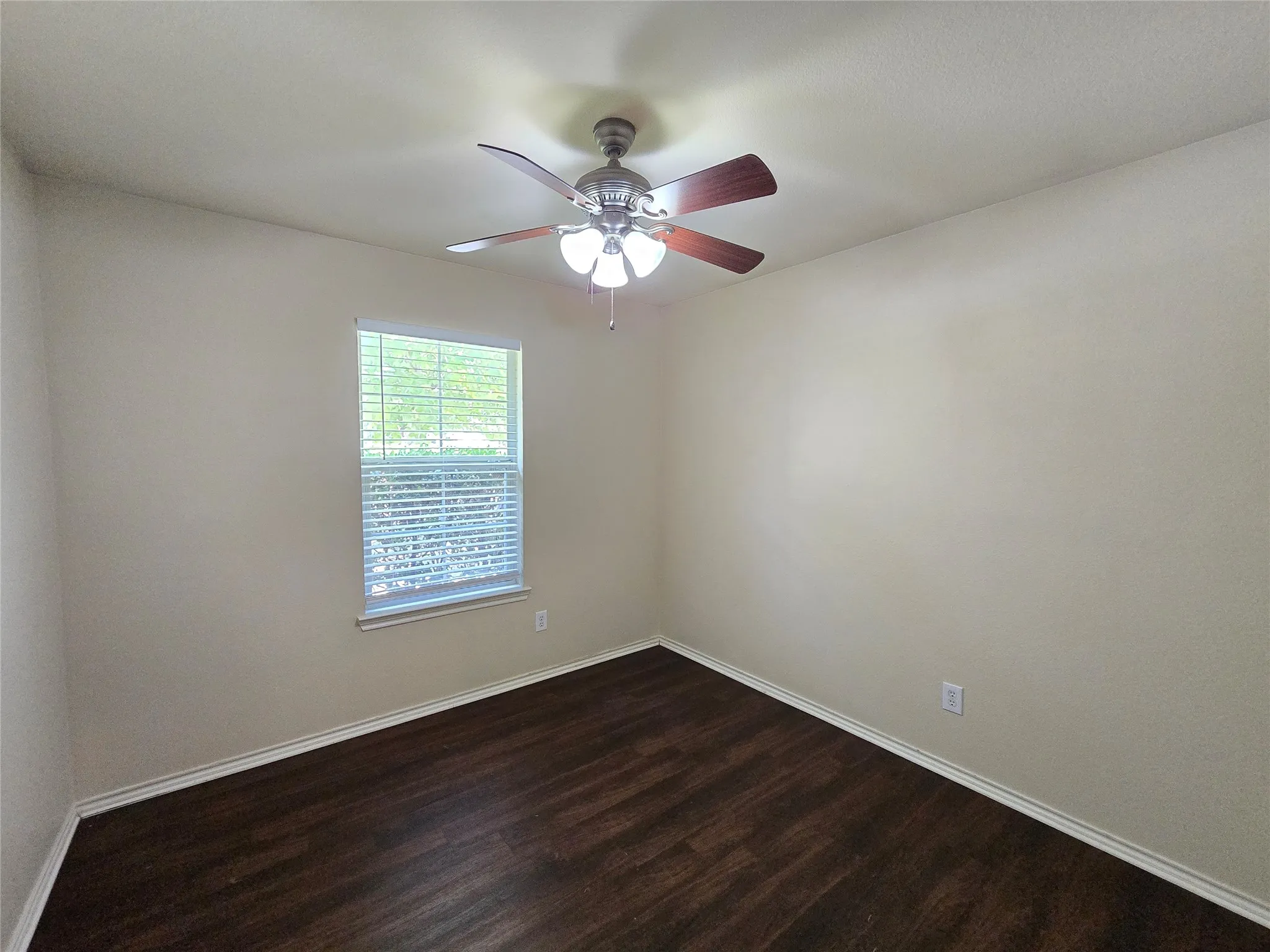 Bedroom 3 looks out to the front yard, and features a ceiling fan and window blinds.