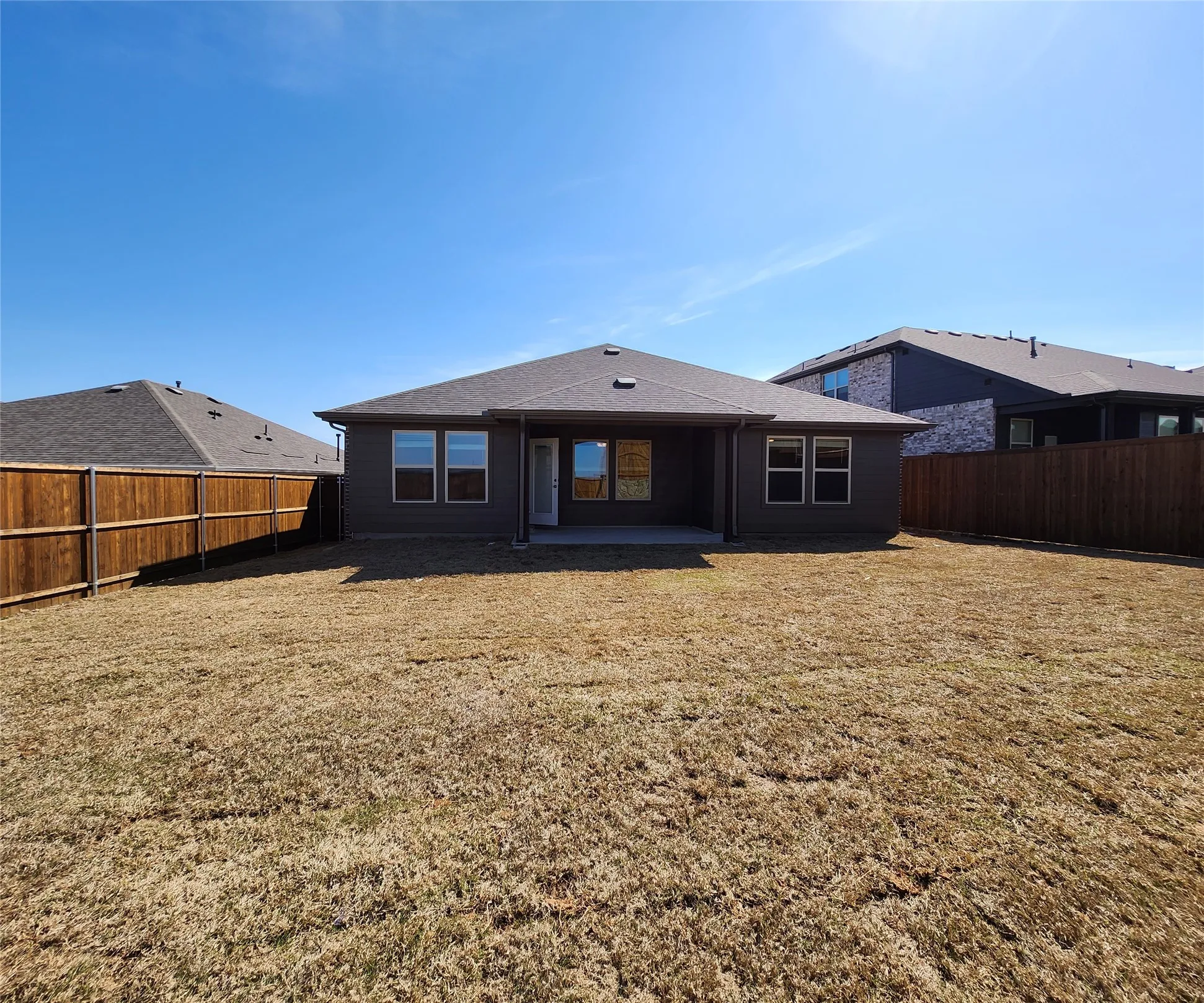 Expansive backyard with a full privacy fence and a concrete patio
