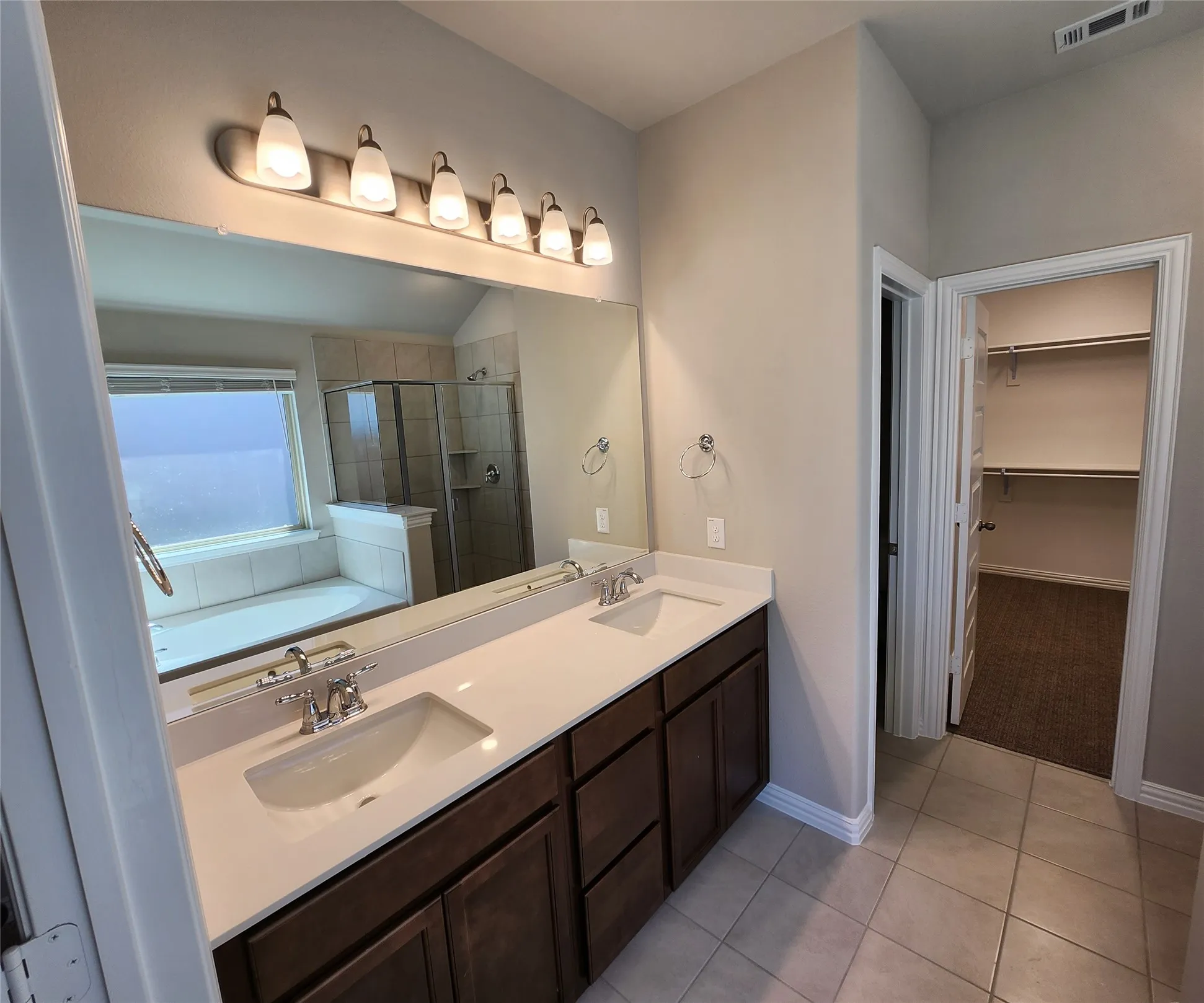 Double vanity with integrated sinks, broad mirror, and warm-toned cabinetry