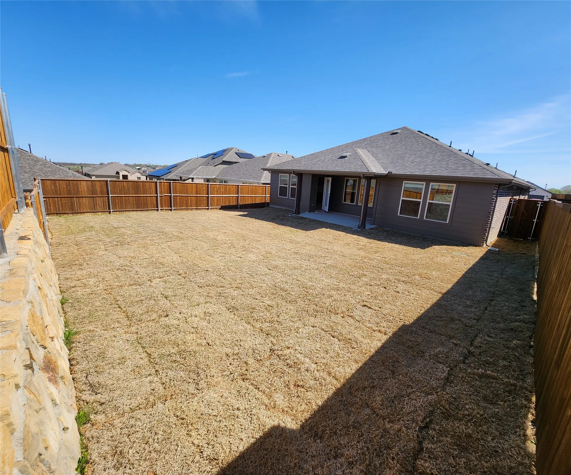 Spacious backyard featuring wood fencing and a stone retaining wall