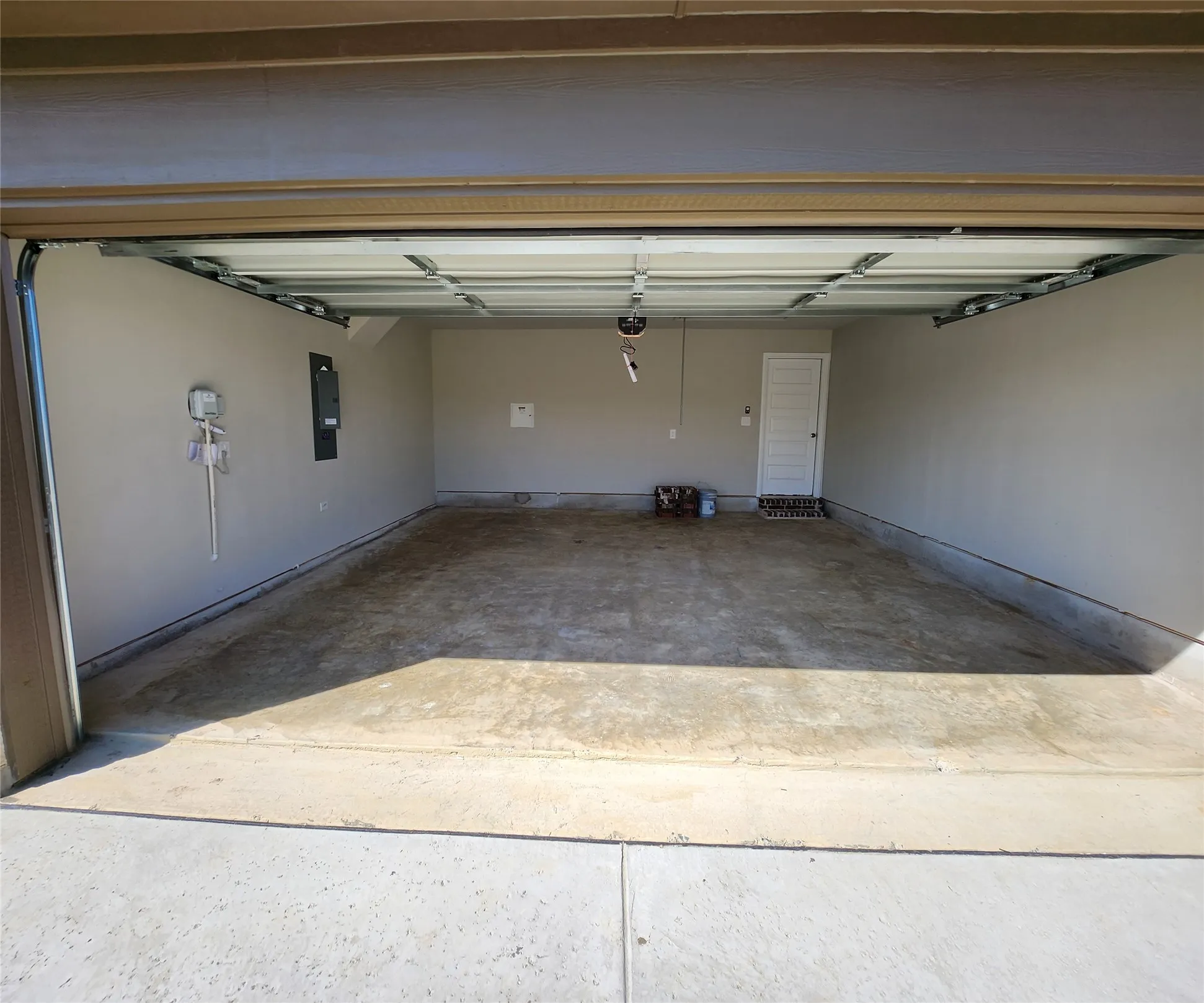 Spacious garage with painted walls, concrete flooring, and an interior access door