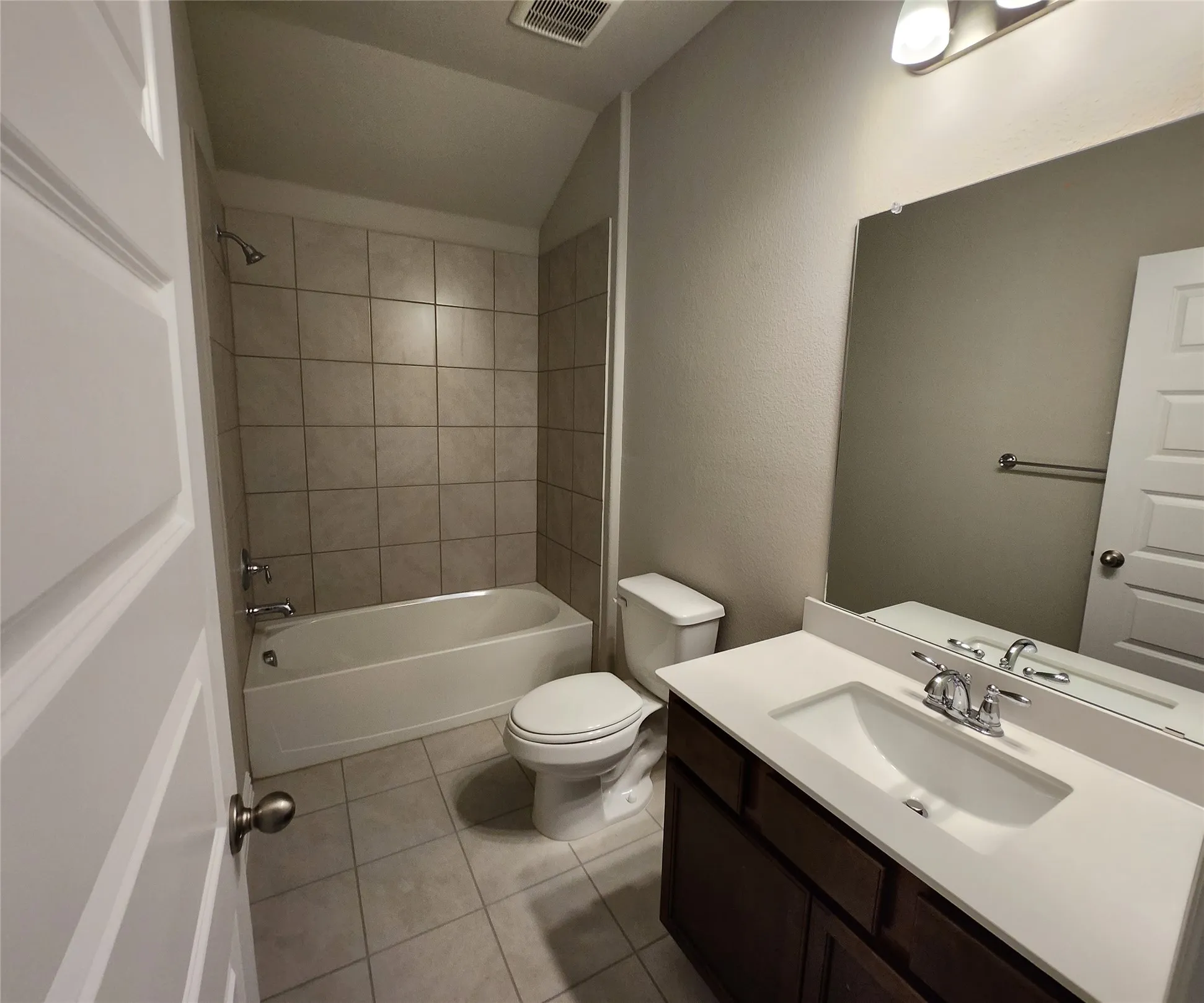 Bathroom featuring a single vanity with a white countertop, chrome fixtures, tile flooring, and a tiled shower-over-tub combination
