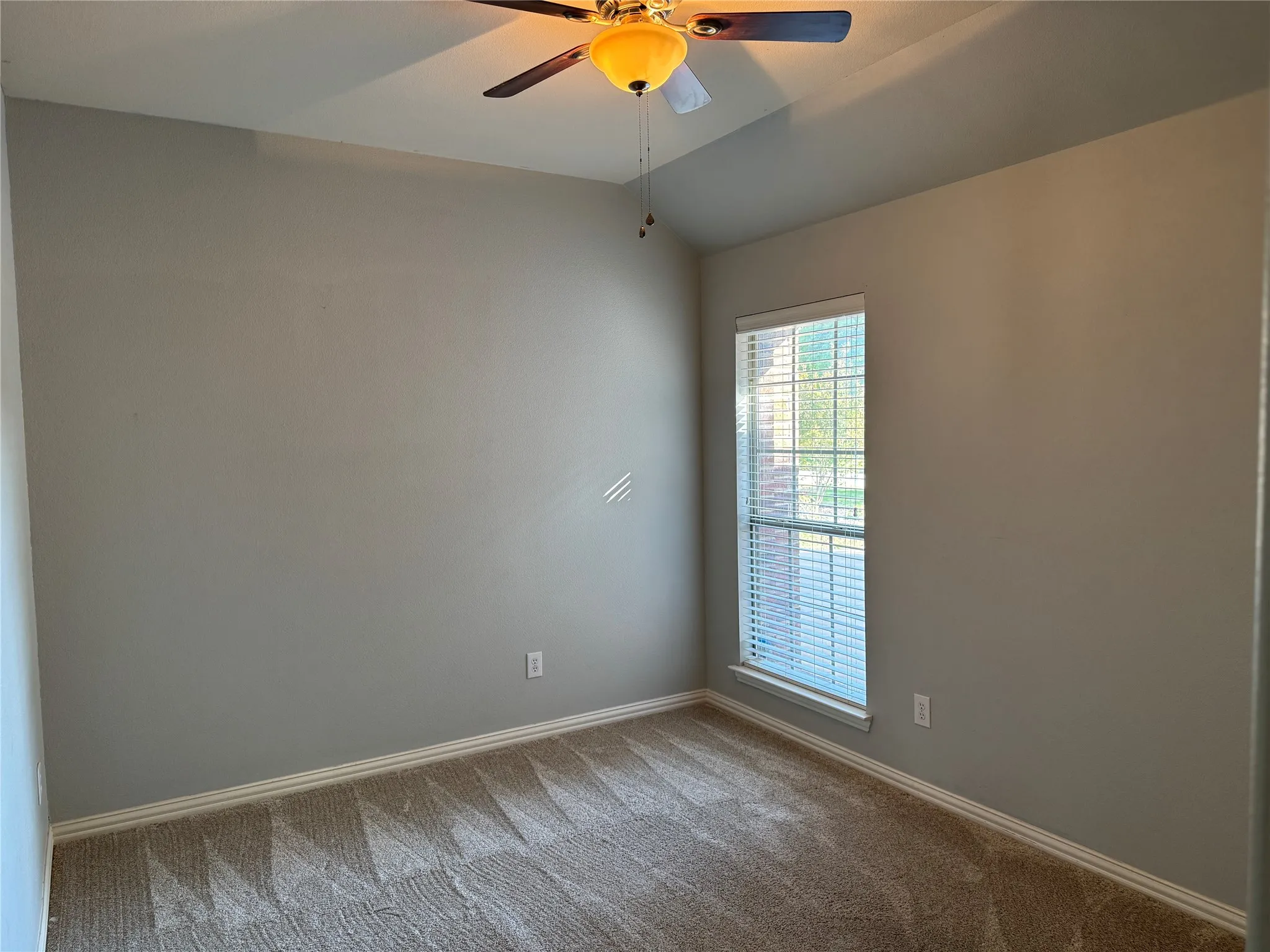 Bedroom featuring ceiling fan, baseboards, vaulted ceiling, and carpet