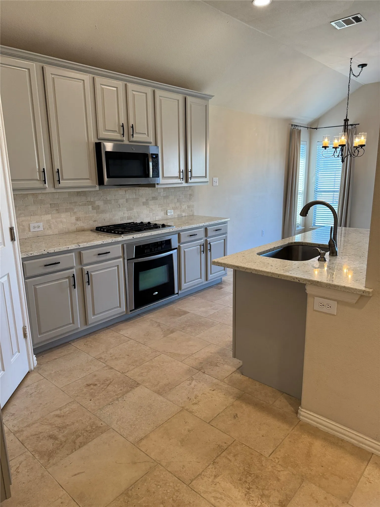 Kitchen with tasteful backsplash, visible vents, a sink, stainless steel appliances, and gray cabinetry