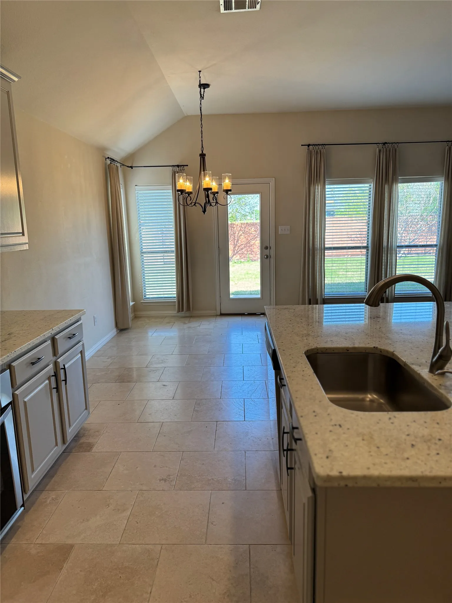 Eat In Kitchen with an inviting chandelier, visible vents, lofted ceiling, a sink, and hanging light fixtures