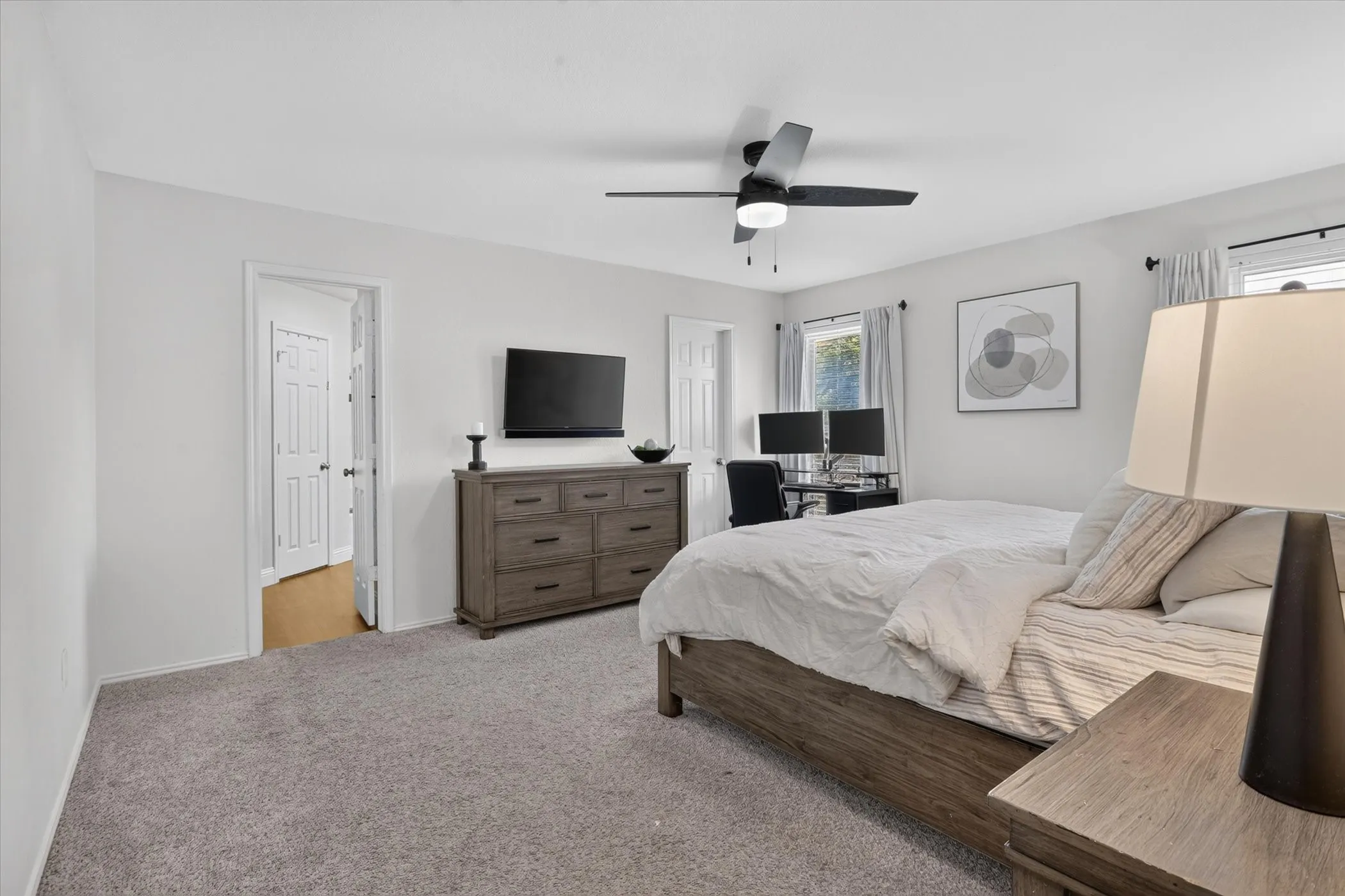 Room featuring light gray carpeting, ceiling fan with integrated lighting, and two windows